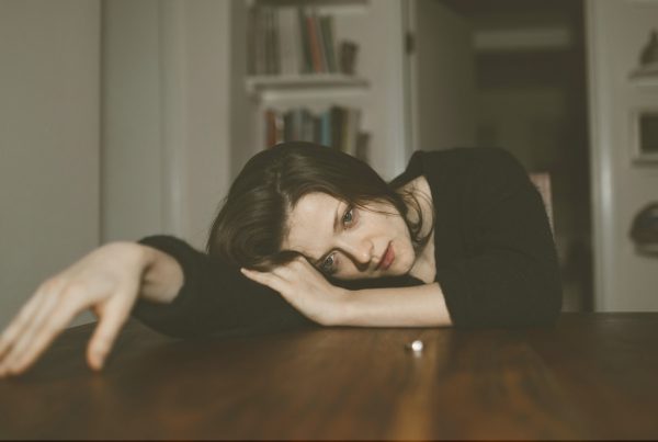 Image of a woman laying on a table, looking sad. Meant to symbolize how someone might feel in a toxic relationship.